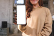 © Farknot Architect - Mockup image of a woman holding and showing mobile phone with blank white screen