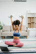 © Nuttapong punna - Woman Doing Yoga and Watching Online Tutorials on Laptop, Training in Living Room at home