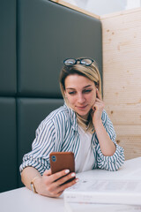 Wall Mural - youthful female student checking updates on smartphone with 4g internet sitting with laptop at cowor