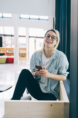 Wall Mural - happy hipster girl smiling at camera and posing during freelance job in coworking space, successful 