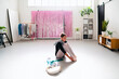 © Studio Marmellata - A ballet dancer stretches in a full split in a bright studio featuring pink decor, indoor plants, and organized furniture, creating an inspiring and tranquil environment.