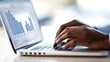 © Akash - Closeup of hands typing on a laptop with financial and market reports on screen