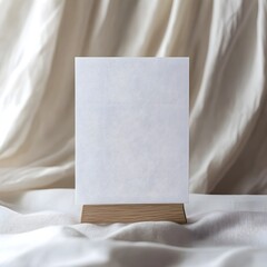 Canvas Print - A blank white card positioned upright on a wooden photo holder, with soft curtains in the background.