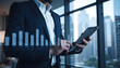 © PTD - Businessman uses digital tablet to analyze financial data in office. modern workspace features city skyline view, emphasizing professionalism and technology