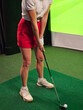 © Nadzeya - Woman practicing golf swing indoors at a virtual golf simulator facility concept