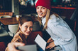 © BullRun - Half length portrait of happy hipster girls dressed in casual outfit smiling at camera while updating application on modern laptop computer with blank screen area connected to wireless 4G internet