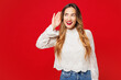 © ViDi Studio - Young curious nosy smiling happy Caucasian woman she wear white blouse casual clothes try to hear you overhear listening intently isolated on plain red background studio portrait. Lifestyle concept.