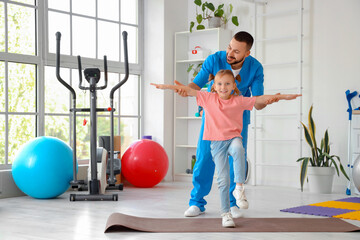 Sticker - Male physiotherapist working with little girl on mat in rehabilitation center