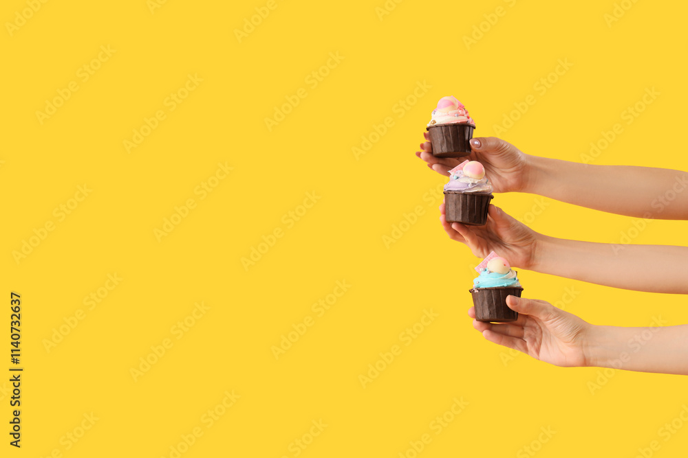 Many female hands with birthday cupcakes on yellow background