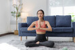 © Crystal - Peaceful asian woman meditating in lotus pose, enjoying her yoga practice in the comfort of her home, promoting mindfulness and inner peace