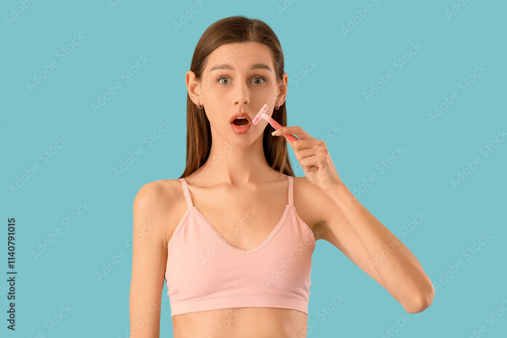 Beautiful shocked young woman with razor on blue background
