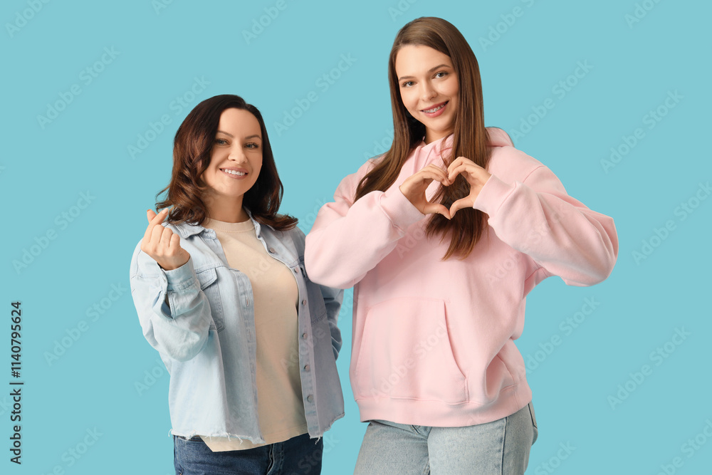 Beautiful happy women showing hearts gestures on blue background