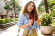 © maxbelchenko - Smiling young woman walking around old street using smartphone. Communication, social networks, online shopping concept.