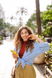 © maxbelchenko - Smiling young woman walking around old street using smartphone. Communication, social networks, online shopping concept.