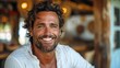 © M_H_L - A smiling man with wavy hair in a cozy, rustic setting.