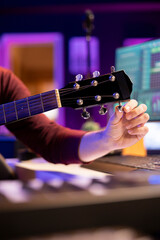 Poster - Musician tuning his acoustic guitar to play and record new tunes, working in his home studio to create new music. Songwriter artist playing instrument with mixing and mastering gear. Close up.