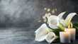 © CreativeCreations - Elegant white calla lilies with lit candles for a peaceful funeral or condolence background on a gray textured backdrop
