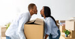 © Prostock-studio - Home relocation concept. Loving african american couple carrying big carton box and trying to kiss, relocating to new home. Young happy homeowners with belongings moving into new property