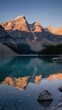 © Soufiane Hamouch - A serene mountain range at sunrise, with golden hues illuminating the peaks and a clear lake.