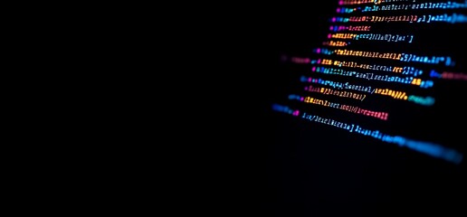 Blurred colorful programming code on black screen.