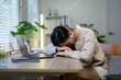 © Parichat - Young asian woman sleeping at her desk after working late at home, feeling overwhelmed by fatigue and stress from relentless deadlines and the pressures of remote work