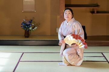 Wall Mural - 着物姿で扇子を持って日本舞踊を踊る年配の日本人女性