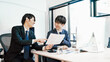 © TAGSTOCK2 - オフィスの社内で社員同士でアイデアを出し合う20代から30代の2人の若手社員の男性