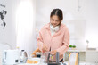 © Wosunan - Asian young woman enjoying bread and coffee for breakfast at home, morning routine before work
