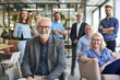 © Asier - Portrait of smiling senior businessman in office with colleagues in the background