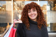 © Cavan Images - Happy shopper holding shopping bags in front of store