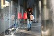 © Cavan Images - Young woman walking and using phone after shopping spree
