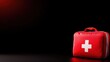 © Chanwit - A red first aid kit with a white cross on a dark background, symbolizing emergency preparedness and health care.