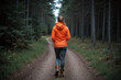 © He - Woman walking through dense forest in orange