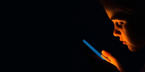 Wall Mural - Young caucasian child gazing at smartphone in dark room illuminated by screen light