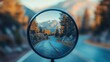 © Suphawan - A close-up of a spherical road mirror showing a sharp curve in a mountain road with trees in the background
