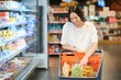 © Serhii - Young satisfied fun woman in casual clothes shopping at supermaket store with grocery cart