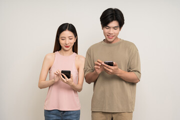 Wall Mural - Happy asian couple attractive in various action gesture using smartphone standing on isolated white background. Cheerful Smiling young man and woman holding cell phone