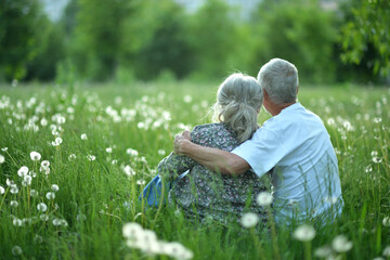 Canvas Print - Portrait of senior couple sitting on the grass in the park