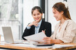© kenchiro168 - Two businesswomen discussing documents at desk with laptop