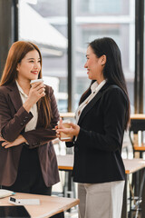 Wall Mural - Two businesswomen talking and smiling in modern office