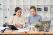 © kenchiro168 - Two women collaborating at desk with laptops and documents