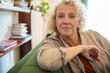 © Marko Geber - Portrait of a confident mature woman sitting on couch smiling at the camera