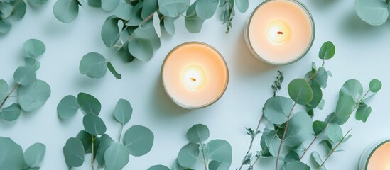 Wall Mural - Elegant flat lay of burning candles and fresh eucalyptus leaves on soft light background for calming atmosphere and wellness aesthetics