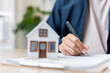 © Sumala - person signing document with house model nearby