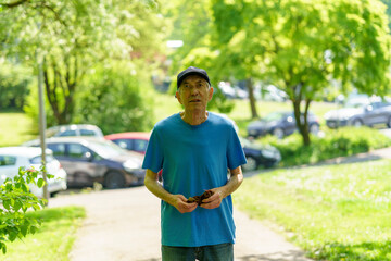 Elderly man in blue t-shirt and cap walking in the park