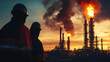 © Nattawut - Team of engineers in hazmat suits analyze the burning chimneys of an oil refinery as smoke fills the sky and industrial pipes surround them.