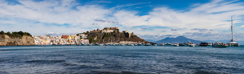 Wall Mural - panoramic view of Coricella town, sea and castle  on beautiful Procida island with colorful houses in sunny summer day  Italy