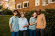 © Maskot - Portrait of happy male and female caregivers standing with senior people near plants in garden