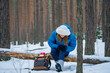 © wifesun - Hiker woman suffering from knee pain after falling in winter forest, first aid kit on backpack