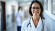 © redflower - Close-up portrait of a smiling, middle-aged female doctor wearing glasses and a white coat in a hospital or clinic.